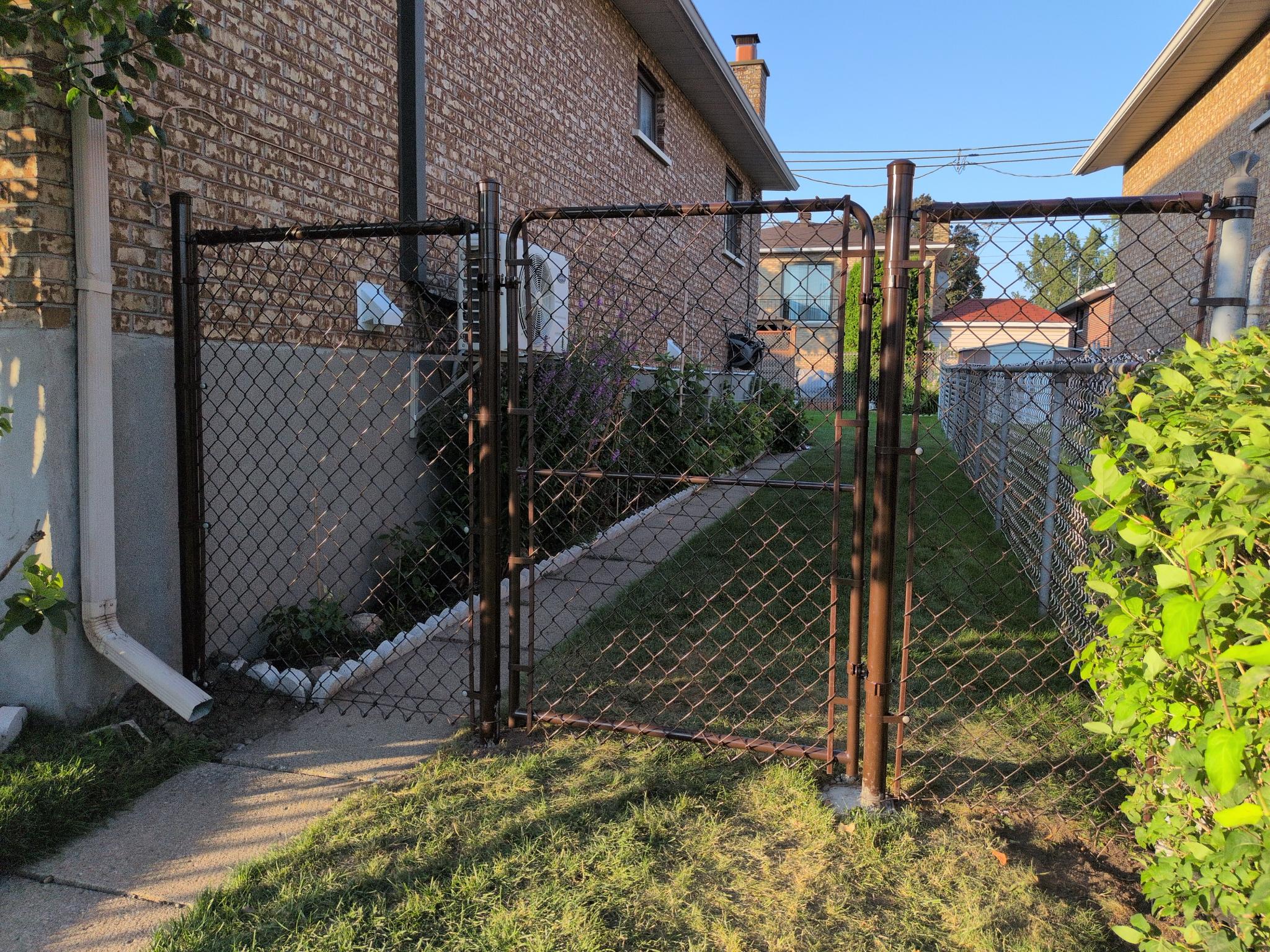 Black chain-link fence with gate between two homes